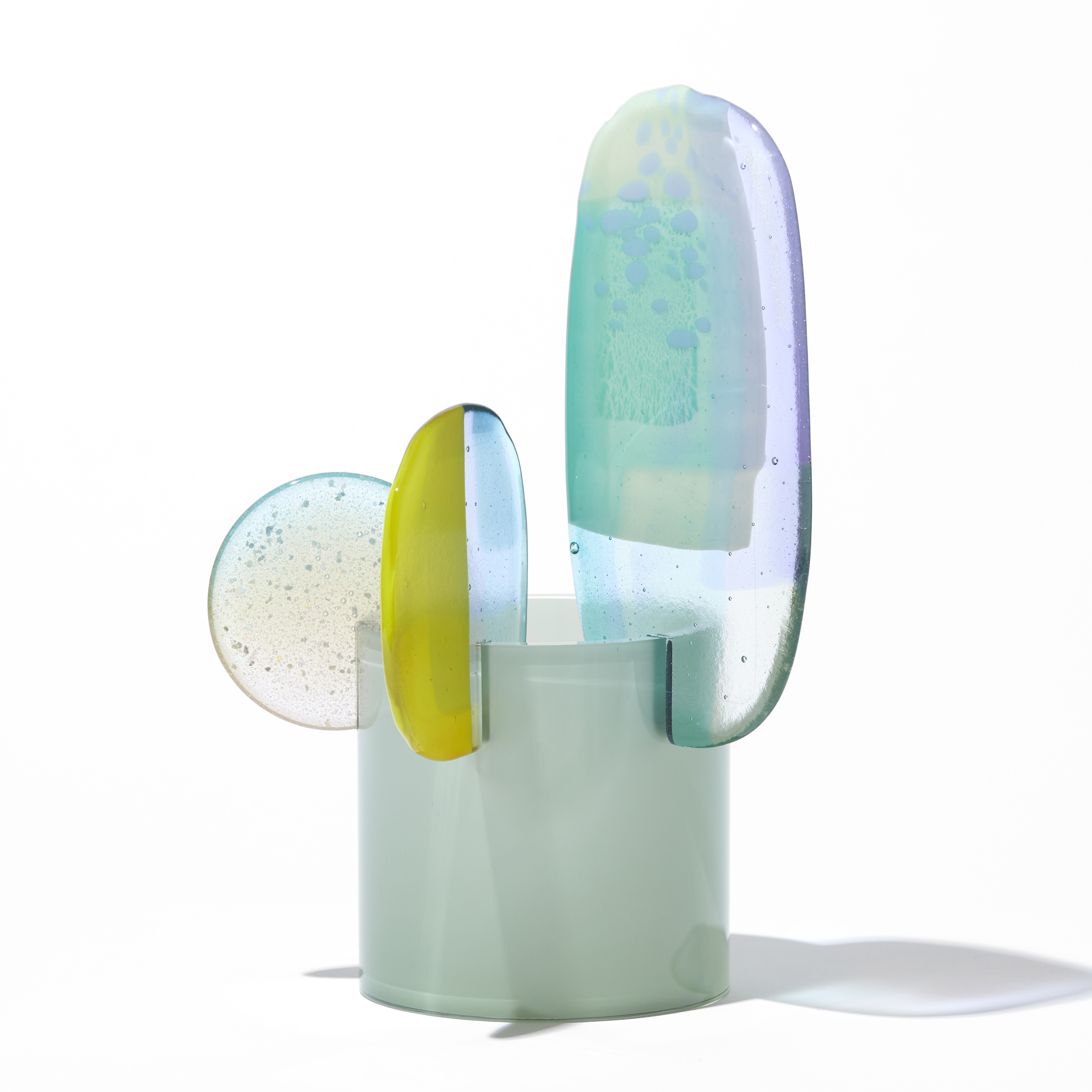 short opaque celadon cylinder with three rounded petals overlapping and perched on the top rim in lilac jade lime green and clear hand made from blown and fused glass